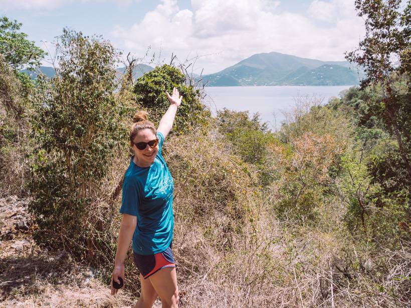 Brunette girl in turquoise shirt standing near view of Tortola on Brown Bay Trail on St. John USVI