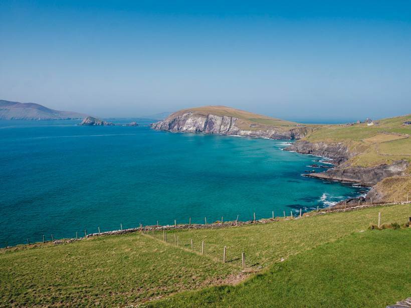 Bright blue and turquoise water meeting low cliffs along the Dingle Peninsula