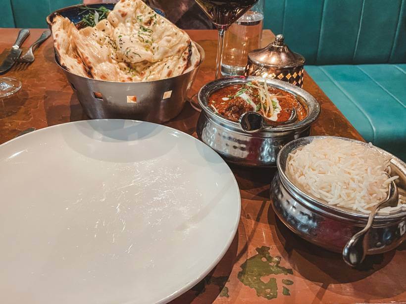 Shiny silver pots of bread, white rice, and sauce at an Indian restaurant in Dublin