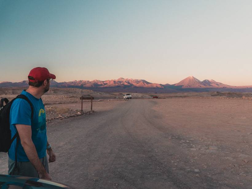 Man standing in baseball cap with bookbag in the Atacama Desert during golden hour