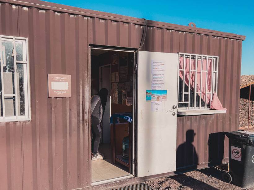 Small brown building with front door open and vivid blue sky behind it