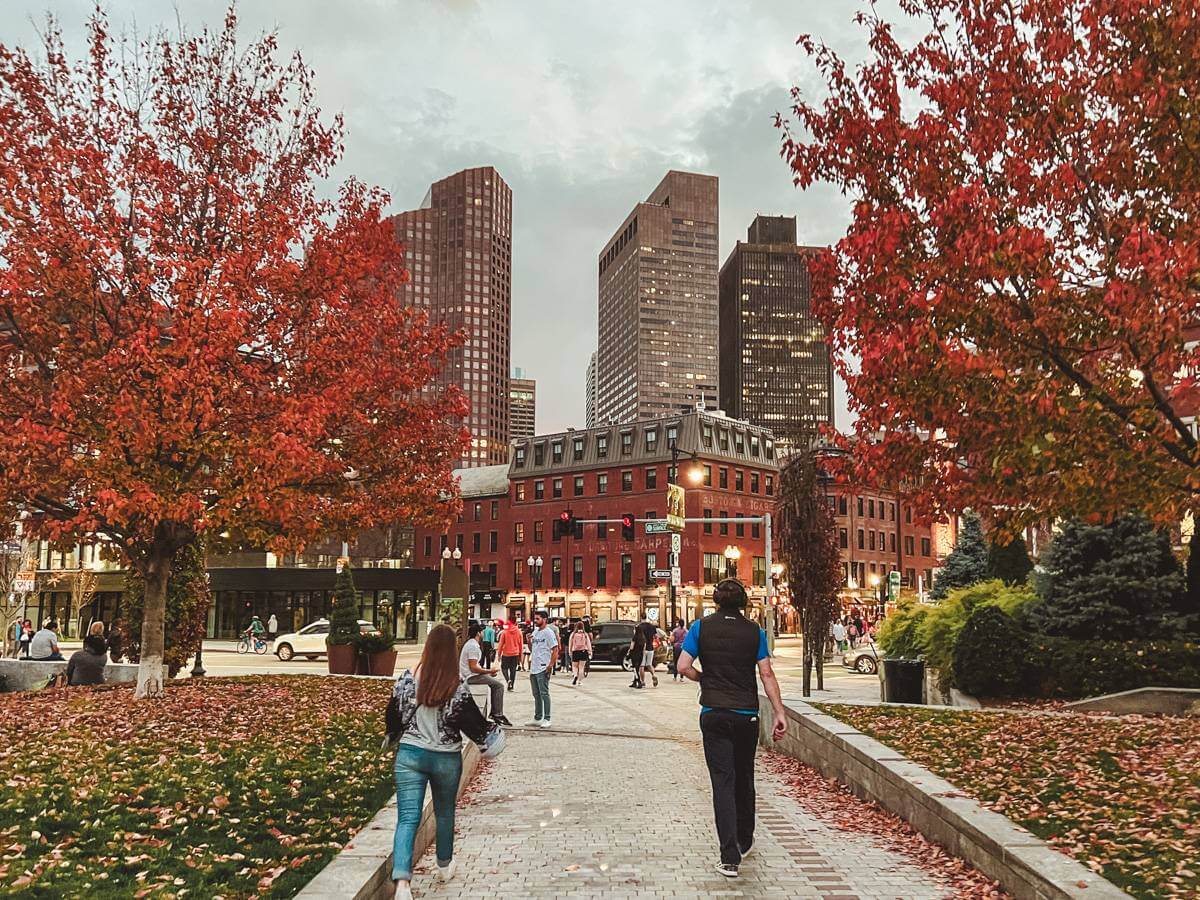 people strolling through downtown boston, ma park with bright red leaves on trees - boston and salem ma itinerary