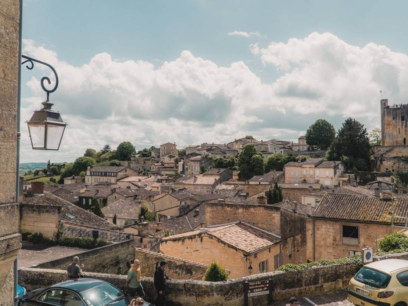 View past hanging lantern over the clay tile rooftops of Saint-Emilion, France during a day trip in Bordeaux